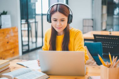  young student wearing headphones studies online, distance learning, and keeps up to date on the global coronavirus pandemic.