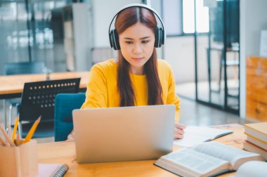  young student wearing headphones studies online, distance learning, and keeps up to date on the global coronavirus pandemic.