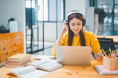  young student wearing headphones studies online, distance learning, and keeps up to date on the global coronavirus pandemic.