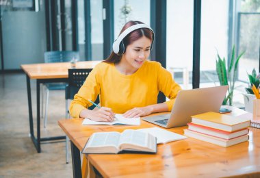  young student wearing headphones studies online, distance learning, and keeps up to date on the global coronavirus pandemic.