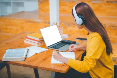  young student wearing headphones studies online, distance learning, and keeps up to date on the global coronavirus pandemic.
