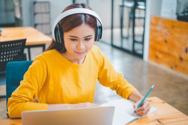  young student wearing headphones studies online, distance learning, and keeps up to date on the global coronavirus pandemic.