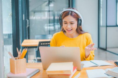 young student wearing headphones studies online, distance learning, and keeps up to date on the global coronavirus pandemic.