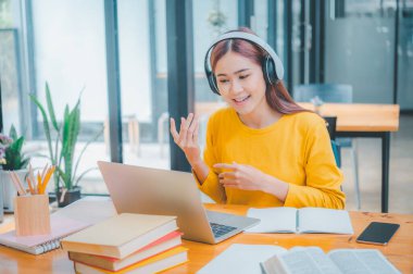 young student wearing headphones studies online, distance learning, and keeps up to date on the global coronavirus pandemic.