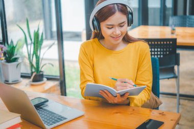 young student wearing headphones studies online, distance learning, and keeps up to date on the global coronavirus pandemic.