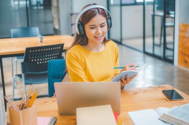 young student wearing headphones studies online, distance learning, and keeps up to date on the global coronavirus pandemic.