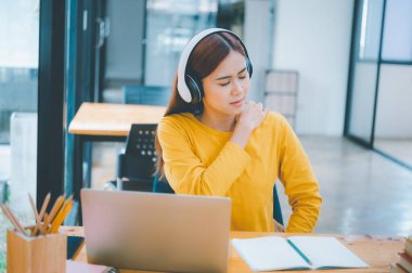 Female students studying online feel aches and pains while sitting online for long periods of time.