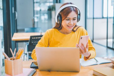 young student wearing headphones studies online, distance learning, and keeps up to date on the global coronavirus pandemic.