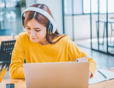 young student wearing headphones studies online, distance learning, and keeps up to date on the global coronavirus pandemic.