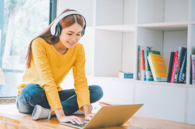 young student wearing headphones studies online, distance learning, and keeps up to date on the global coronavirus pandemic.