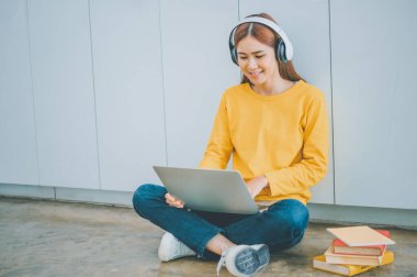 young student wearing headphones studies online, distance learning, and keeps up to date on the global coronavirus pandemic.