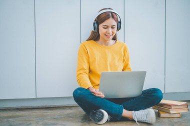 young student wearing headphones studies online, distance learning, and keeps up to date on the global coronavirus pandemic.