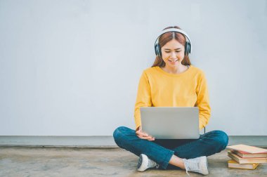 young student wearing headphones studies online, distance learning, and keeps up to date on the global coronavirus pandemic.
