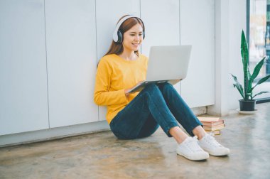 young student wearing headphones studies online, distance learning, and keeps up to date on the global coronavirus pandemic.