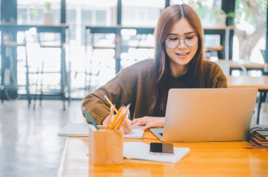 young student wearing headphones studies online, distance learning, and keeps up to date on the global coronavirus pandemic.