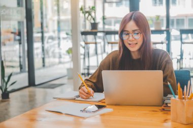 young student wearing headphones studies online, distance learning, and keeps up to date on the global coronavirus pandemic.