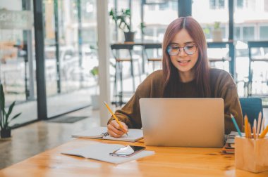 young student wearing headphones studies online, distance learning, and keeps up to date on the global coronavirus pandemic.