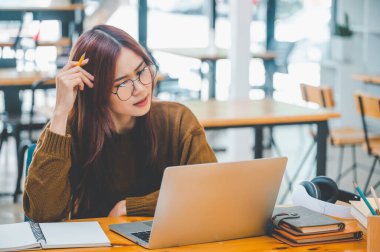 young student wearing headphones studies online, distance learning, and keeps up to date on the global coronavirus pandemic.