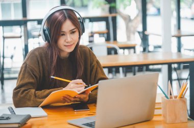 young student wearing headphones studies online, distance learning, and keeps up to date on the global coronavirus pandemic.