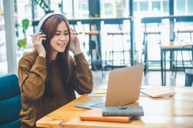 young student wearing headphones studies online, distance learning, and keeps up to date on the global coronavirus pandemic.