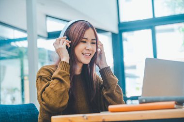 young student wearing headphones studies online, distance learning, and keeps up to date on the global coronavirus pandemic.