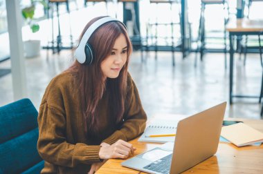 young student wearing headphones studies online, distance learning, and keeps up to date on the global coronavirus pandemic.
