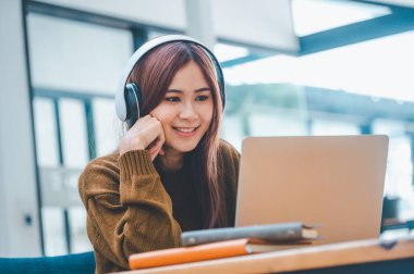 young student wearing headphones studies online, distance learning, and keeps up to date on the global coronavirus pandemic.