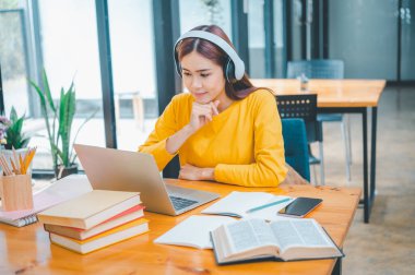 young student wearing headphones studies online, distance learning, and keeps up to date on the global coronavirus pandemic.