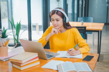 young student wearing headphones studies online, distance learning, and keeps up to date on the global coronavirus pandemic.