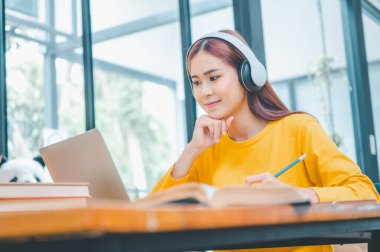 young student wearing headphones studies online, distance learning, and keeps up to date on the global coronavirus pandemic.
