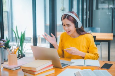 young student wearing headphones studies online, distance learning, and keeps up to date on the global coronavirus pandemic.