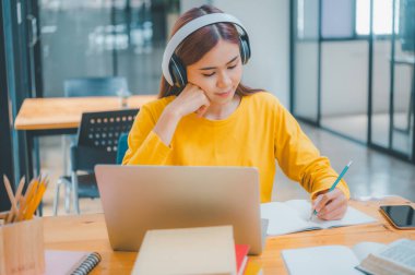 young student wearing headphones studies online, distance learning, and keeps up to date on the global coronavirus pandemic.