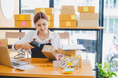 Small business owners online are scanning barcode-labelled parcel boxes with a barcode scanner to verify their product orders. of online retailers - online shopping