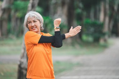 Elderly, white-haired Asian woman exercising in the park early in the morning.