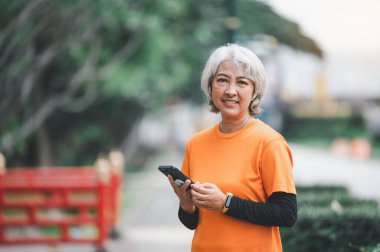Yaşlı, beyaz saçlı Asyalı kadın sabahın erken saatlerinde parkta egzersiz yapıyor..