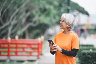 Yaşlı, beyaz saçlı Asyalı kadın sabahın erken saatlerinde parkta egzersiz yapıyor..