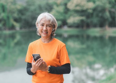Yaşlı, beyaz saçlı Asyalı kadın sabahın erken saatlerinde parkta egzersiz yapıyor..