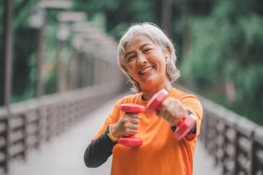 Yaşlı, beyaz saçlı Asyalı kadın sabahın erken saatlerinde parkta egzersiz yapıyor..