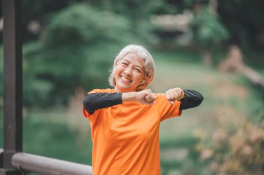 Yaşlı, beyaz saçlı Asyalı kadın sabahın erken saatlerinde parkta egzersiz yapıyor..