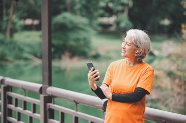 Yaşlı, beyaz saçlı Asyalı kadın sabahın erken saatlerinde parkta egzersiz yapıyor..