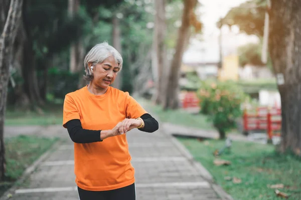 Elderly, white-haired Asian woman exercising in the park early in the morning.