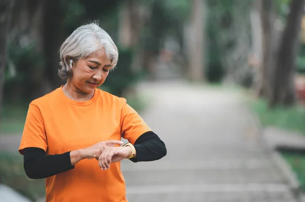 Elderly, white-haired Asian woman exercising in the park early in the morning.