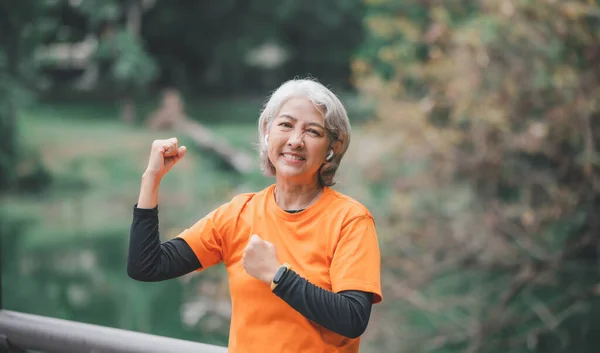 Elderly, white-haired Asian woman exercising in the park early in the morning.