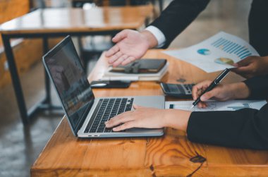 Analiz, kavramsal analiz ve iş planlaması için grafik şarj ederek ofiste birlikte çalışan ve iletişim kuran bir grup iş adamı