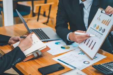 Analiz, kavramsal analiz ve iş planlaması için grafik şarj ederek ofiste birlikte çalışan ve iletişim kuran bir grup iş adamı