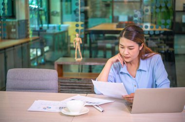 Asyalı iş kadını ahşap masa, vergi, muhasebe, istatistik ve analitik araştırma konseptinde matematik finansmanı için dizüstü bilgisayar kullanıyor.