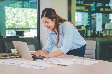 Asyalı iş kadını ahşap masa, vergi, muhasebe, istatistik ve analitik araştırma konseptinde matematik finansmanı için dizüstü bilgisayar kullanıyor.