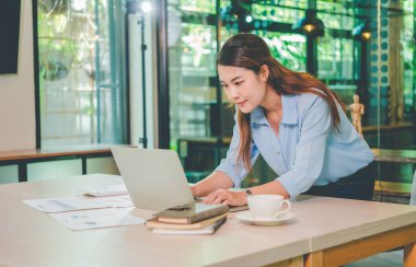 Asyalı iş kadını ahşap masa, vergi, muhasebe, istatistik ve analitik araştırma konseptinde matematik finansmanı için dizüstü bilgisayar kullanıyor.