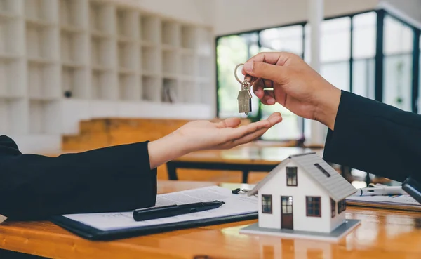 Salesperson Concept of holding house keys, house keys for a new home, new home purchase. a loan agreement for real estate, a loan deal for real estate, a loan agreement for real estate