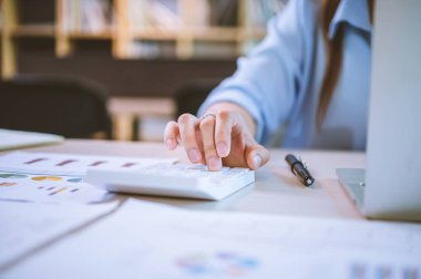 İş yapan Asyalı kadın çalışmak için hesap makinesini kullanarak ofiste masa başında oturuyor. İş Konsepti Analizi ve Planlaması